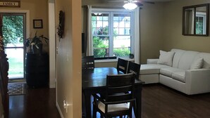 A dining area with a dark wooden table and chairs, a white sofa, and a ceiling fan. - Shallow Lake Retreat (Shallow Lake)