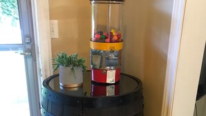 A wooden barrel with a red and yellow dispenser, a potted plant, and a glass container with colorful items. - Shallow Lake Retreat (Shallow Lake)