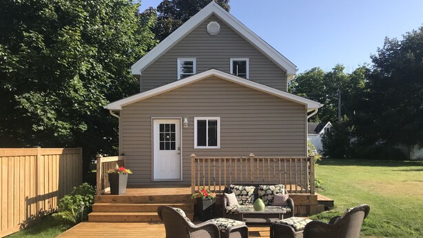 A two-story house with a front porch, a wooden deck, and a fenced yard. - Shallow Lake Retreat (Shallow Lake)