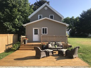 A two-story house with a front porch, a wooden deck, and a fenced yard. - Shallow Lake Retreat (Shallow Lake)