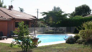A swimming pool with a tiled deck, surrounded by a fence, and a house with a tiled roof and satellite dish. - Family home at the foot of the Pyrenees (Clarac)