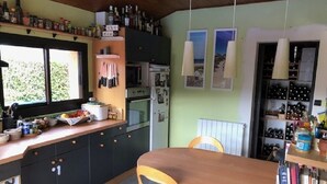 A kitchen with a wooden table and chairs, a window, and various kitchen appliances. - Family home at the foot of the Pyrenees (Clarac)