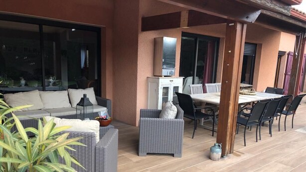 An outdoor patio area with a sofa, wicker chairs, a dining table, and a TV. - Family home at the foot of the Pyrenees (Clarac)