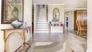 A spacious foyer with a staircase, a large mirror, and a wooden cabinet. - Halifax Riverfront Oasis - 8 Bedrooms with pool (Daytona Beach)