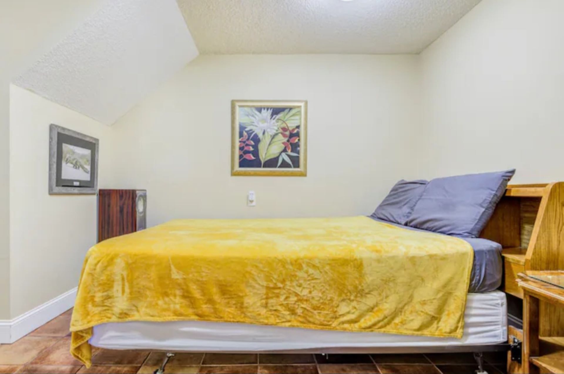 Una camera da letto con un letto, una testiera in legno, un quadro appeso al muro e una piccola credenza in legno.