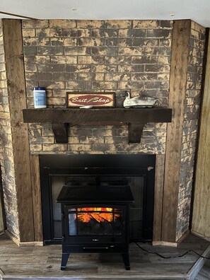 A fireplace with a brick wall, a sign above it, and a shelf with items.