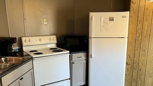 Une cuisine de taille réduite, avec un four blanc, un four à micro-ondes et un réfrigérateur.