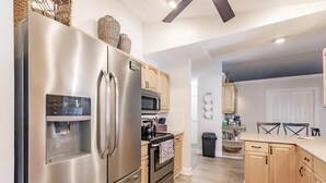 A modern kitchen with stainless steel appliances, wooden cabinets, and a built-in water dispenser.