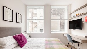 A modern bedroom with a bed, a desk, and a TV. - Bright Spacious Modern One Bedroom Apartment (1) (London)