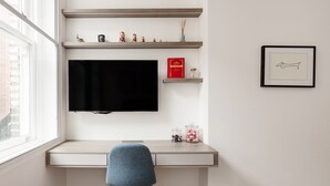 A modern room with a desk, a chair, a TV, and shelves with decorative items. - Bright Spacious Modern One Bedroom Apartment (1) (London)