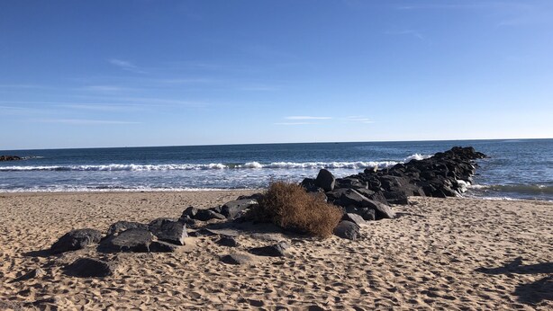 Une plage avec un rivage rocheux et des vagues qui déferlent sur le sable.