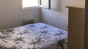 Une chambre à coucher avec un lit, une fenêtre, un radiateur et un tableau accroché au mur.