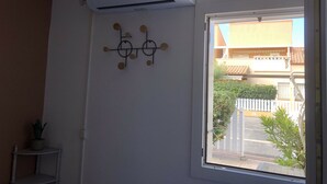 Une pièce avec un climatiseur blanc, un élément décoratif fixé au mur et une fenêtre donnant sur un quartier résidentiel.