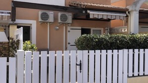 Un bâtiment avec une clôture blanche en bois, des unités de climatisation et une porte portant le numéro « 18 ».