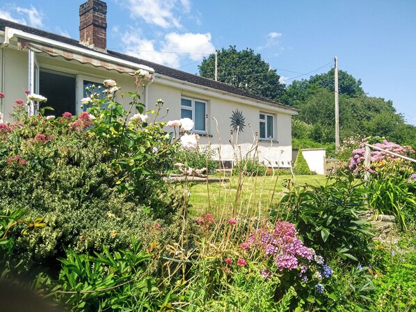 A house with a garden in front, a chimney, and a white door.