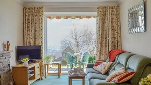 A living room with a television, a sofa, a small table, and a view of the outdoors. - 3 bedroom accommodation in Blakeney Hill, near Lydney, Forest of Dean (Blakeney Hill, near Lydney, Forest of Dean)
