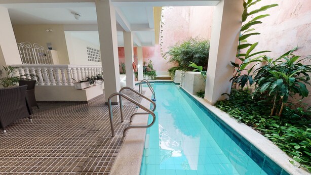 A pool area with a tiled floor, metal pool ladder, and surrounding greenery. - -APARTMENT CIUDAD VIEJA-PLAZA BOLIVAR THIRD FLOOR- (Cartagena de Indias)