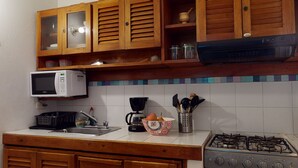 A kitchen with wooden cabinets, a microwave, a gas stove, a coffee maker, and a sink. - -APARTMENT CIUDAD VIEJA-PLAZA BOLIVAR THIRD FLOOR- (Cartagena de Indias)