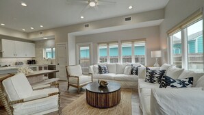 A spacious living room with a white sofa set, a wooden coffee table, and a dining area with white cabinets and a kitchen counter. - Modern Beauty in Old Town w/Spa Feel.HEATED Private pool-Special Winter discount (Port Aransas)