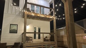 A two-story house with a balcony, outdoor seating, and a swimming pool. - Modern Beauty in Old Town w/Spa Feel.HEATED Private pool-Special Winter discount (Port Aransas)