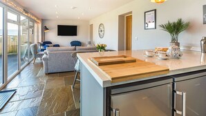 Een moderne keuken met een groot eiland, inbouwapparatuur en een zithoek met een bank en stoelen.
