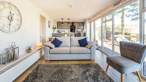 Een moderne woonkamer met een grijze bank, een zwart tapijt en een grijze fauteuil.