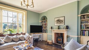 A cozy living room with a fireplace, a television, and a bookshelf.