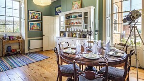A dining area with a round table set for four, surrounded by wooden chairs with cushioned seats.