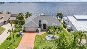 A coastal property with a large house, a driveway, and a view of the ocean. - River View, Heated pool - Serenity & Sunrises - Roelens Vacations (Cape Coral)
