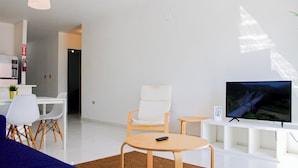 A modern living room with a flat-screen TV, a sofa, a chair, and a small table. - Arecibo Hotel 2103 (Arecibo)