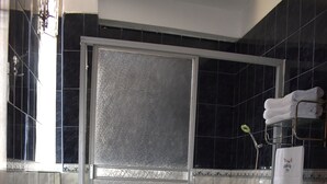 Un baño con ducha de vidrio, inodoro blanco y lavamanos.