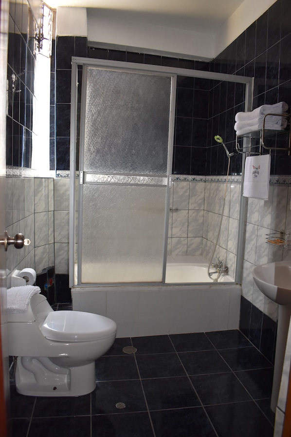 Un baño con ducha de vidrio, inodoro blanco y lavamanos.