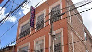 Un hotel con letrero, balcones y tejado de baldosas.