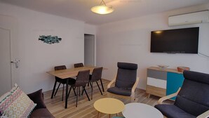 A modern living room with a dining area, a sofa, a TV, and a small table.