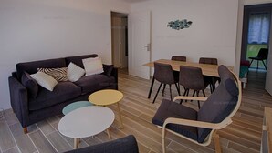 A modern living room with a sofa, a dining table with chairs, and a small coffee table.