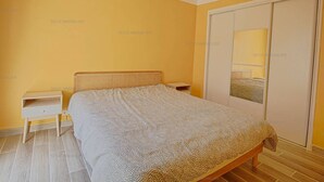A bedroom with a bed, nightstands, a wardrobe, and a mirror.