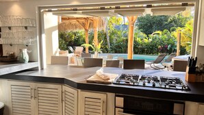 A kitchen with a gas stove, a sink, and a view of a pool area with lounge chairs.