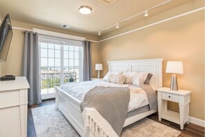 Relax in this serene bedroom with a large bed, TV, and window offering a view of the outdoors.