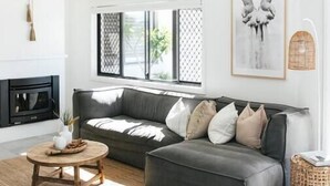 Een moderne woonkamer met een grijze modulaire bank, een ronde houten salontafel en een open haard.