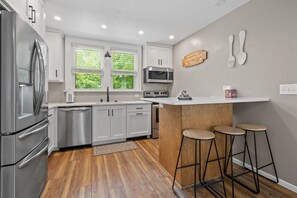 A modern kitchen with stainless steel appliances, white cabinets, and a wooden island with stools.