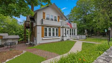 A two-story house with a balcony, a front yard, and an American flag.