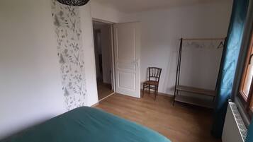 A room with a bed, a chair, a radiator, and a door leading to another room.