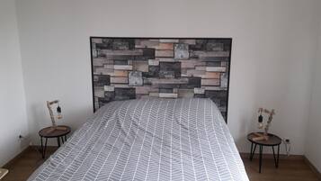 A bedroom with a bed, a wall-mounted headboard, two bedside tables, and a small rug.