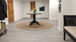 A room with a round table at the center, a bench on the right, and a door at the back. - Beautifully Renovated Space in Lawrenceville Home, WiFi, Smart TV in All Rooms! (Lawrenceville)