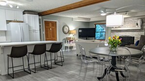 A modern kitchen with white cabinets, a built-in refrigerator, and a dining area with a glass table and chairs. - Beautifully Renovated Space in Lawrenceville Home, WiFi, Smart TV in All Rooms! (Lawrenceville)