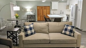 A living room with a beige sofa, two checkered pillows, a small table, and a lamp. - Beautifully Renovated Space in Lawrenceville Home, WiFi, Smart TV in All Rooms! (Lawrenceville)
