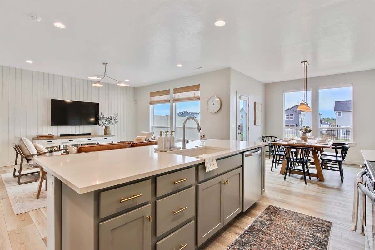 A modern kitchen with a large island, built-in appliances, and a dining area with a view.
