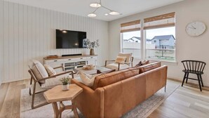 Ein modernes Wohnzimmer mit einer Couch, Sesseln, einem Couchtisch, einem Fernseher und einem Fenster mit Blick.