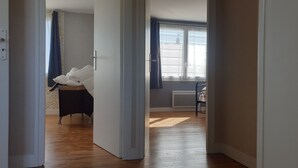 A room with a bed, a radiator, and a window with curtains. - House equipped for 1-8 people (modular) (Montfarville)