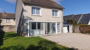 A two-story house with a large glass conservatory, a gravel driveway, and a well-maintained lawn. - House equipped for 1-8 people (modular) (Montfarville)